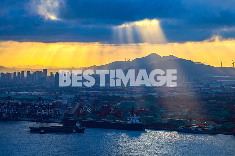 Des rayons de soleil percent les nuages , illuminant les installations portuaires de Qianwan (Chine)